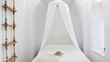 Una cama con dosel blanco, una escalera de madera y un ventanal.