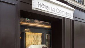 The entrance of Hôtel La Comtesse with a modern design, a marble reception desk, and a dark-toned exterior. - Hôtel La Comtesse (Paris)
