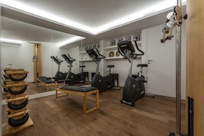A gym with exercise equipment, wooden benches, and a mirror wall.