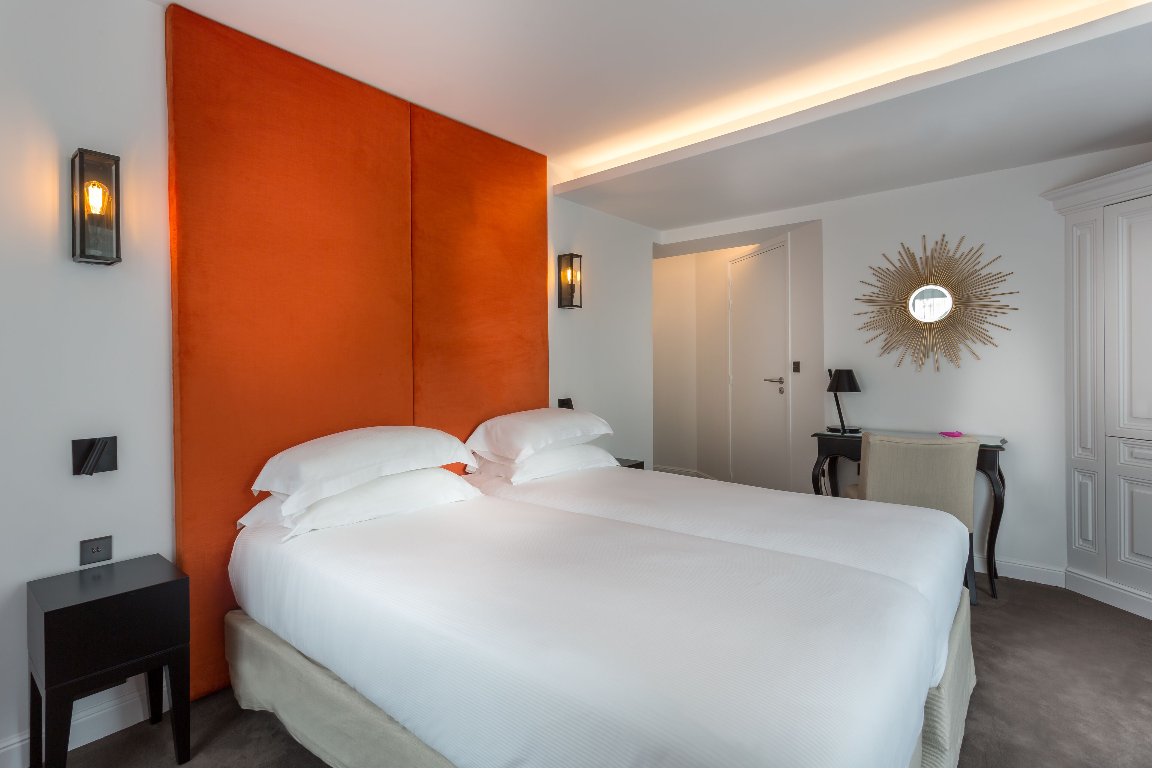 A hotel room with a large bed, a nightstand, a desk, and a chair.