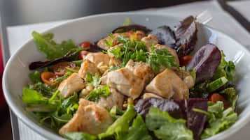 Een saladekom met verschillende soorten sla en stukjes kip.