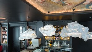 A bar area with a ceiling mural, bar shelves with bottles, and a modern chandelier. - Hôtel La Comtesse (Paris)