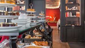 A buffet with various food items and a bookshelf in the background. - Hôtel La Comtesse (Paris)