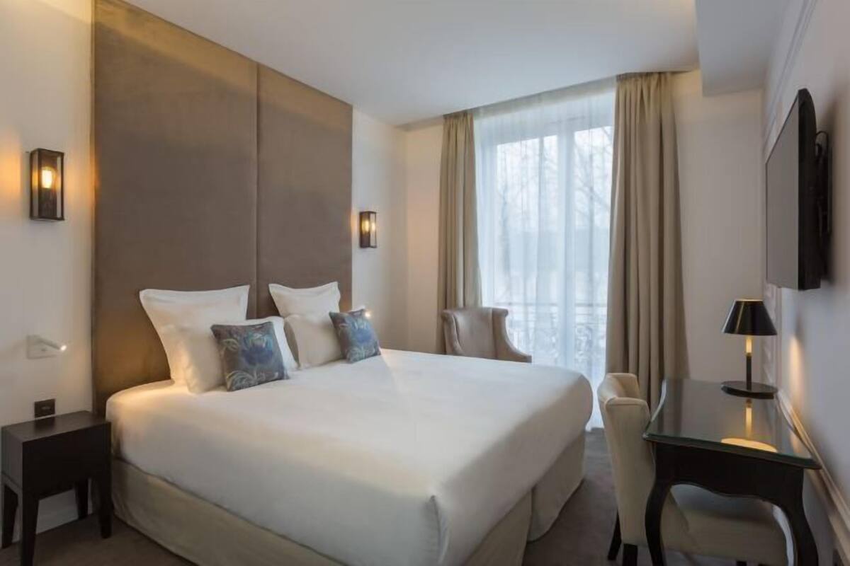 Une chambre d’hôtel avec un grand lit, un bureau, une chaise et un téléviseur.