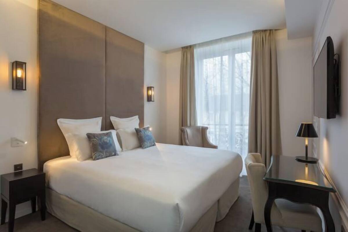 Une chambre d’hôtel avec un grand lit, des tables de chevet, un bureau et une chaise.