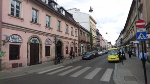 A street with pink buildings, a yellow bus, and a pedestrian crossing.