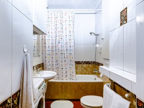 A bathroom with a sink, toilet, bathtub, and shower curtain with various symbols.