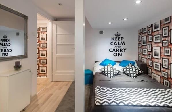 Ein Schlafzimmer mit einem Bett, einer Wand mit gerahmten Bildern und einem motivierenden Zitat.