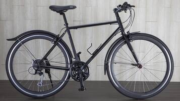 A stationary bicycle with a black frame and seat, positioned against a wooden wall.