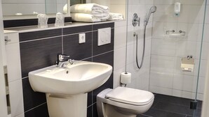 Een moderne badkamer met een wastafel, toilet en douche.