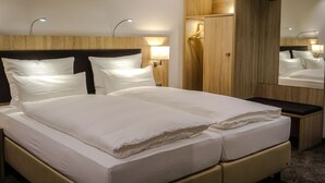 Een hotelkamer met een groot bed, nachtkastjes, een spiegel en houten wandbekleding.
