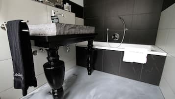 Un baño moderno con lavamanos de mármol, lavabo pedestal negro y un perchero para toallas.