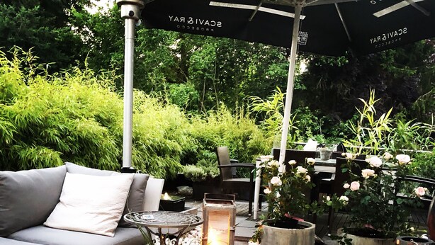 An outdoor seating area with a sofa, tables, and potted plants. - VillaAdel Designroom (Alsfeld)