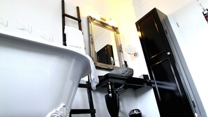 A bathroom with a white bathtub, a black vanity, a mirror, and a black door. - VillaAdel Designroom (Alsfeld)