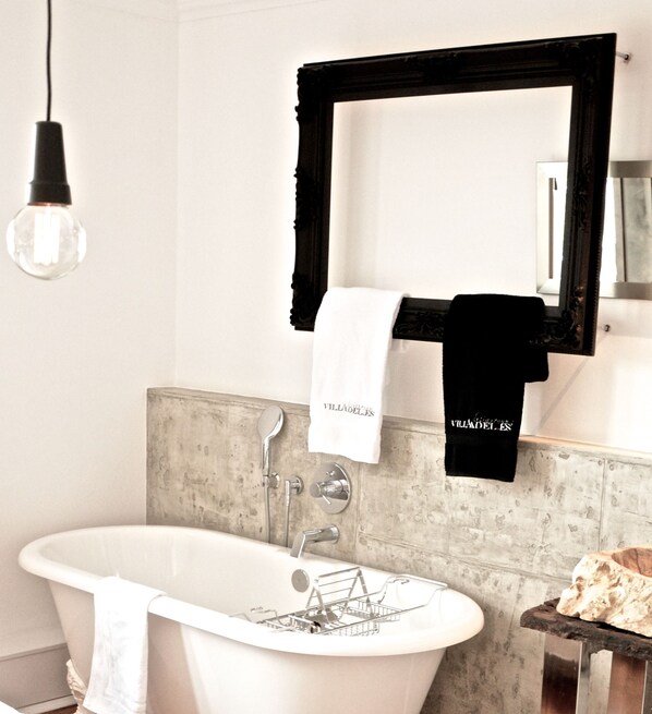 A bathroom with a freestanding bathtub, a towel rack with a white towel, a black towel, and a mirror with a black frame. - VillaAdel Designroom (Alsfeld)