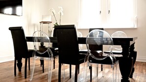 A dining area with a black table and chairs, a TV mounted on the wall, and a window with natural light. - VillaAdel Designroom (Alsfeld)