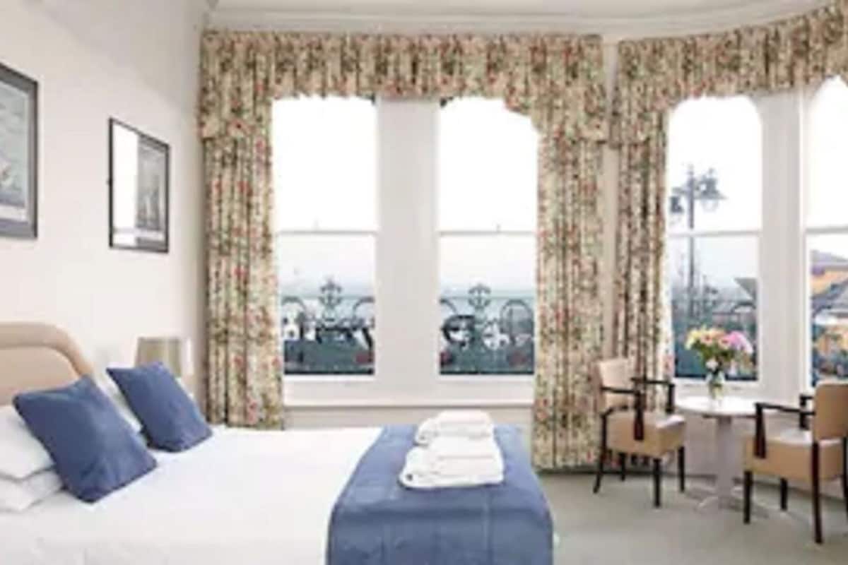 Quarto de hotel com cama, escrivaninha e vista para a cidade.