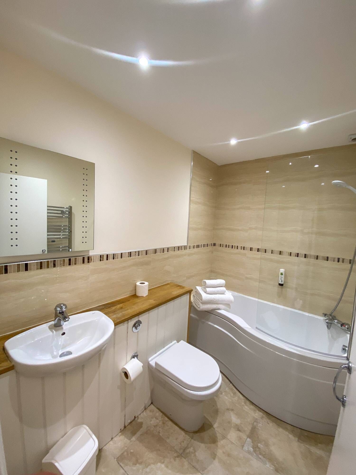 A modern bathroom with a sink, toilet, and bathtub.