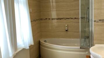 Un baño moderno con ducha a ras de suelo, bañera independiente y tocador con lavamanos.