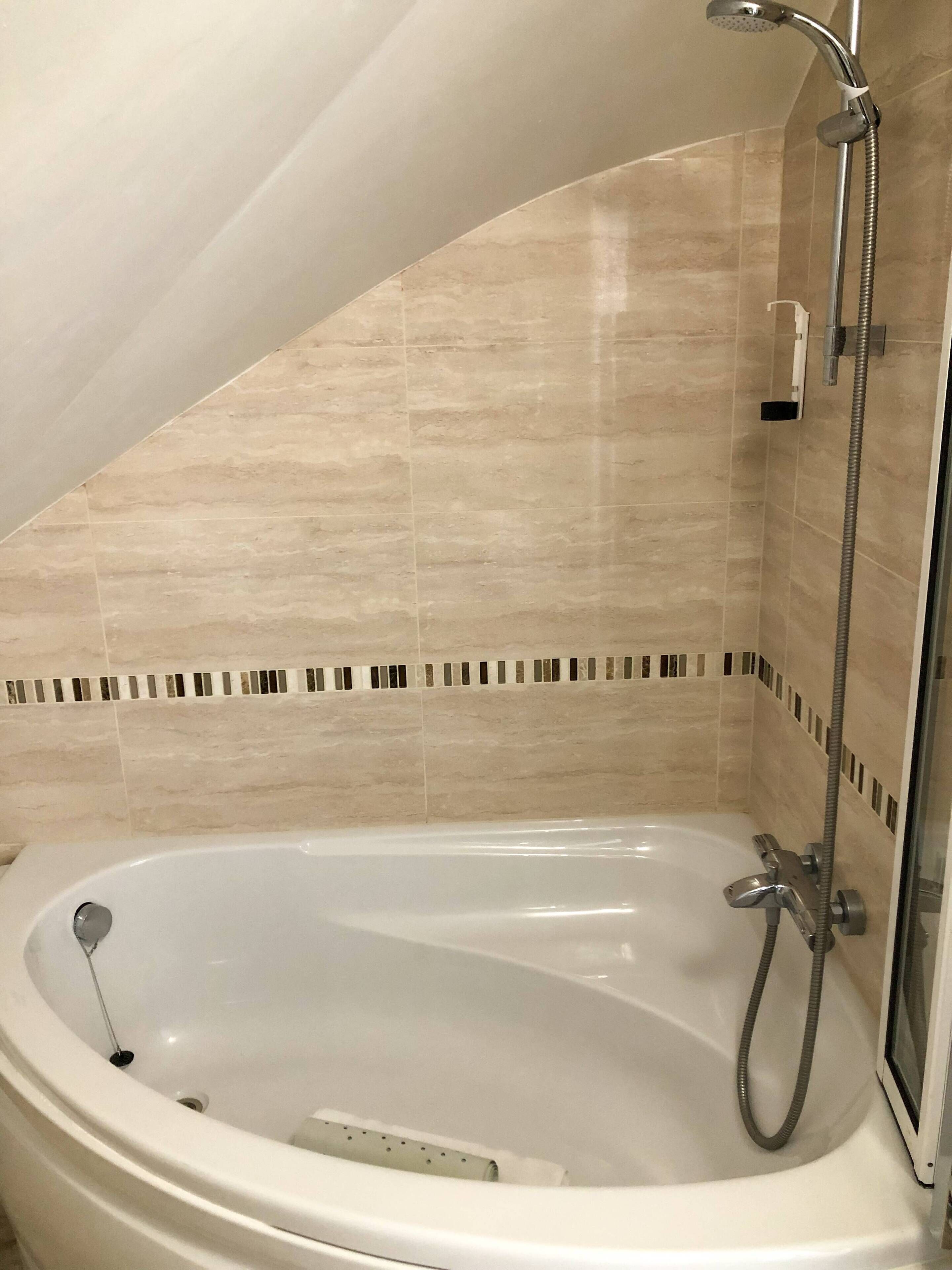 A modern bathroom with a freestanding bathtub, a showerhead, and a tiled floor.