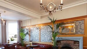 Un vestíbulo de hotel con asientos de cuero, una chimenea y un candelabro.