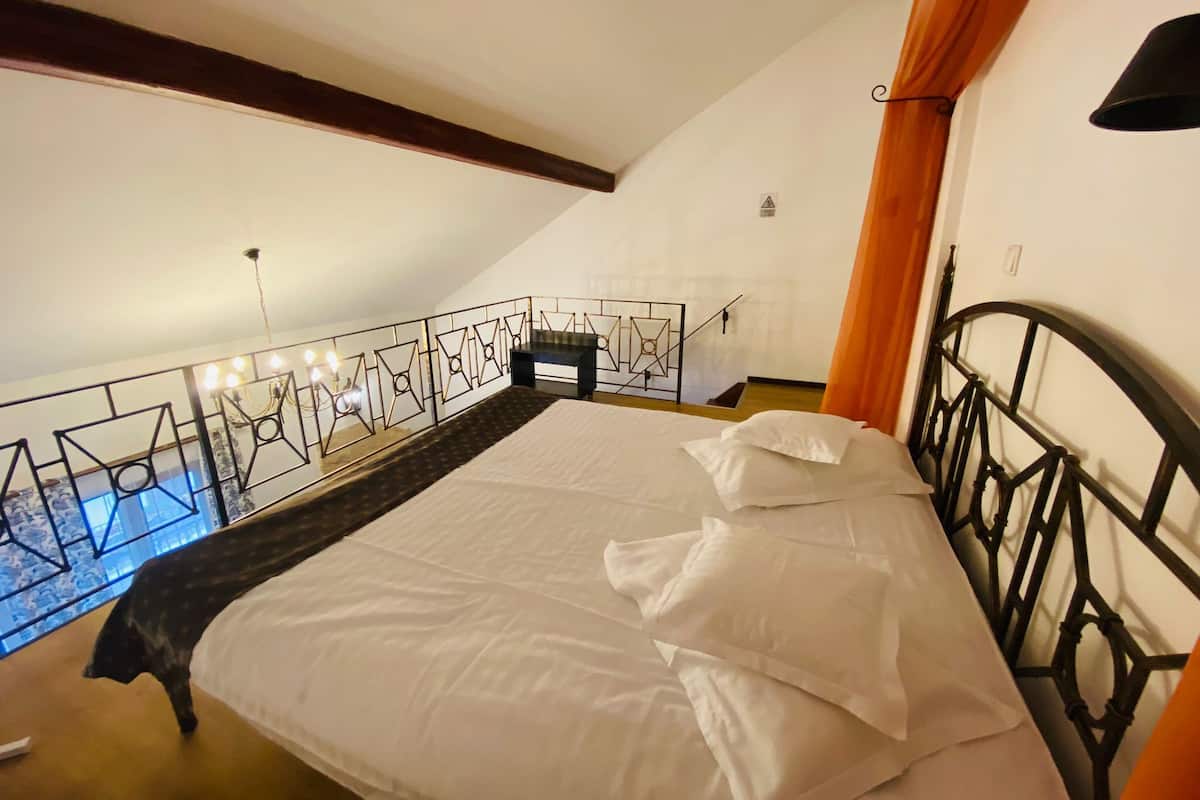 A bedroom with a bed, a view of the outside, and a balcony railing.