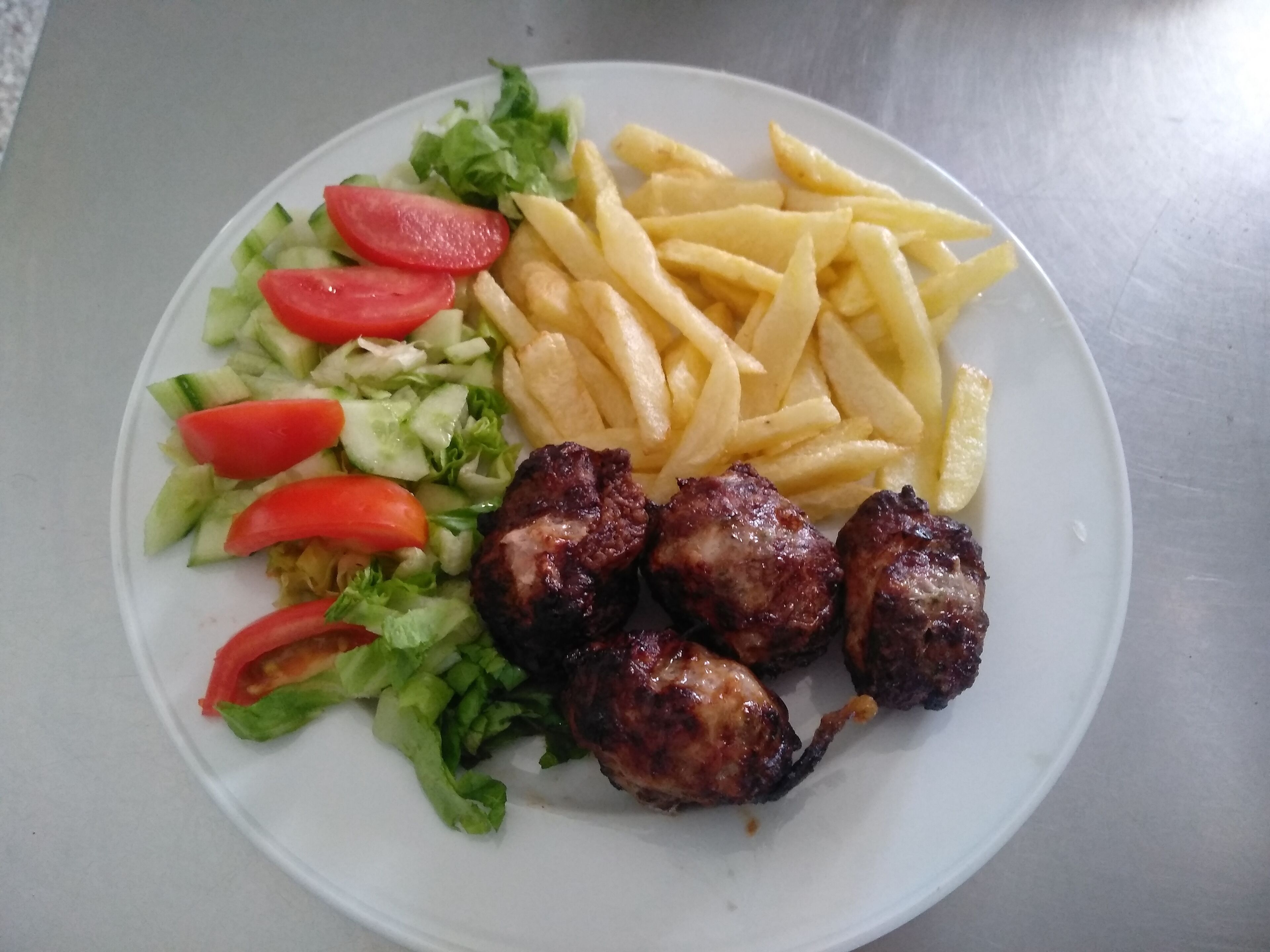 A plate with grilled meat, French fries, and a salad.