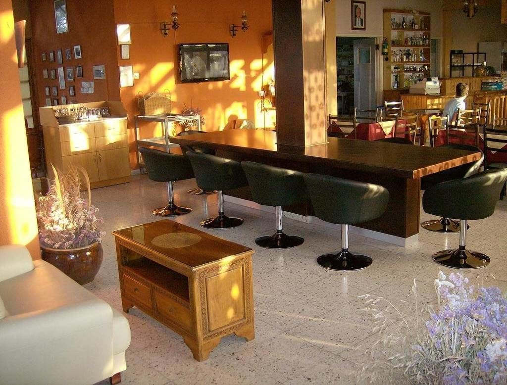 A bar area with a long counter and multiple stools, a seating area with a sofa and a small table, and a kitchen visible in the background.