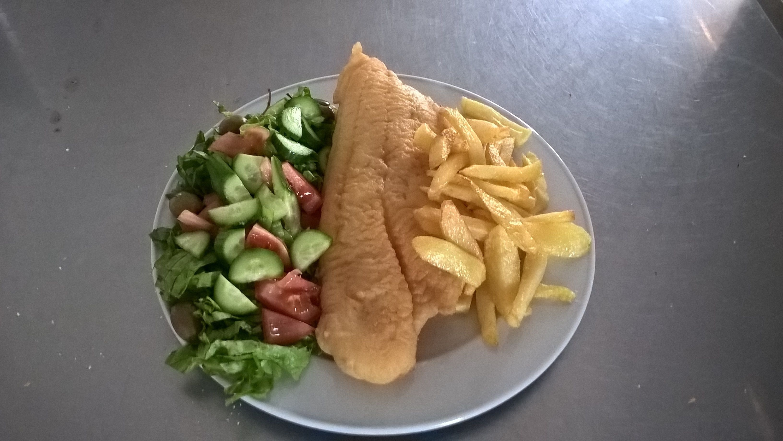 Ein Teller mit Fischfilet, Pommes und gemischtem Blattsalat.