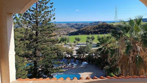 A pool area with lounge chairs and a view of the landscape. - Rantzo Holiday Apartments (Pissouri)