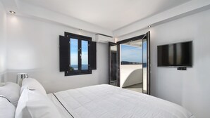 Una habitación de hotel moderna con una cama grande, un televisor de pantalla plana y un balcón con vistas a la ciudad.