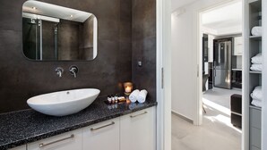 Un baño moderno con un lavamanos blanco grande, un espejo y una vela pequeña en la encimera.