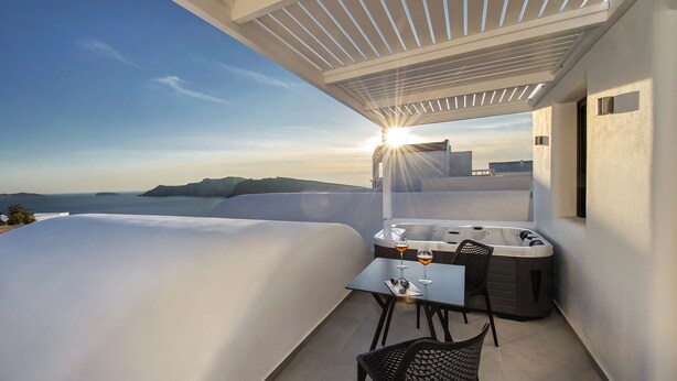 Un balcón con hidromasaje, mesa y sillas, con vistas panorámicas.