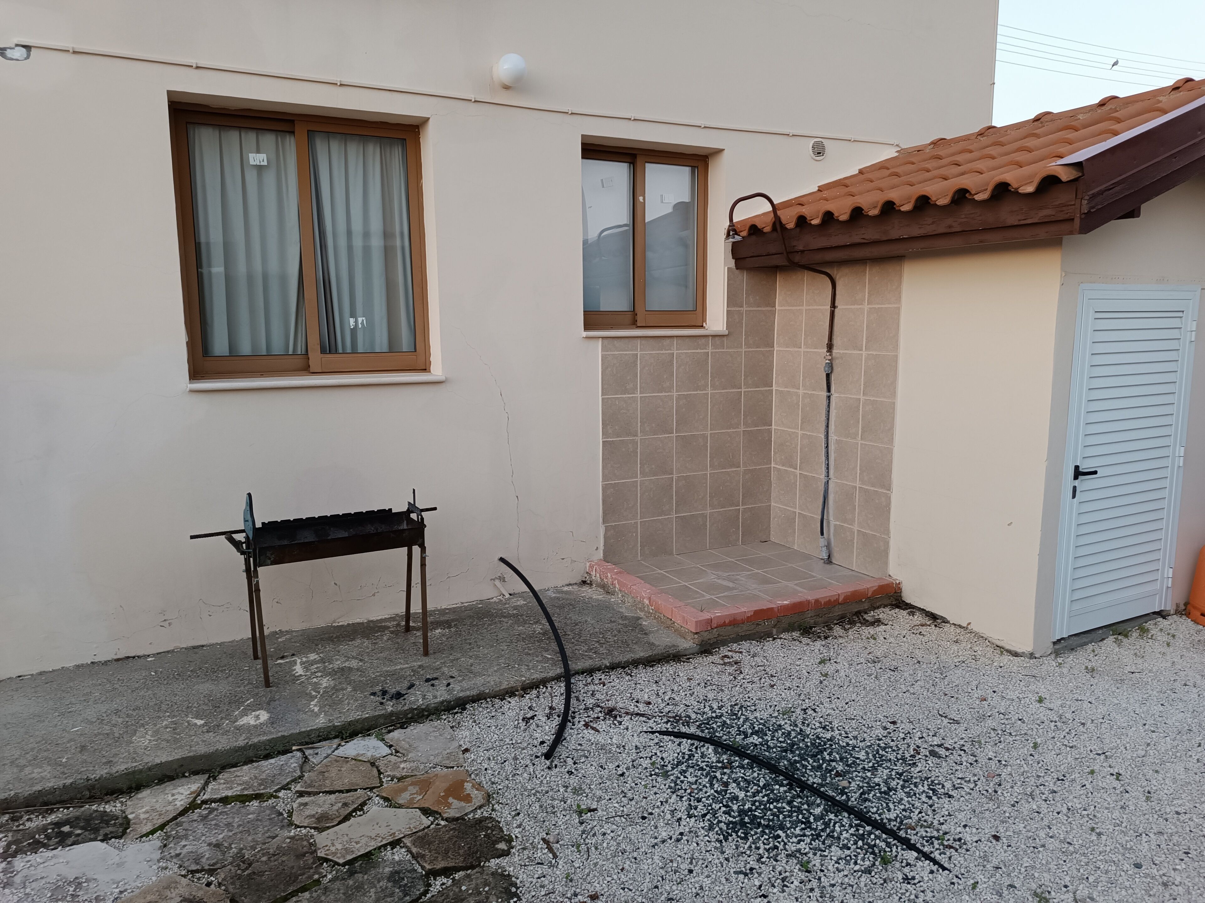A building with a tiled exterior, a small outdoor area with a bench, and a door.