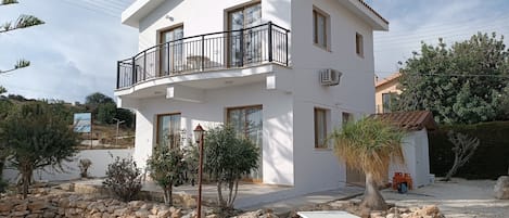 Un edificio de dos pisos con balcón, piscina y pared de piedra.