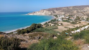A coastal town with a beach, houses, and a hilly landscape. - Kapsalia Holiday Villas (Pissouri)