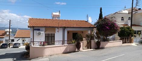 A small building with a tiled roof, a satellite dish, and a sign that reads "CHIMOKPATISIE DIOROTIKIAS."