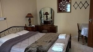Une chambre à coucher avec un lit, une commode, un miroir, une lampe et une chaise.