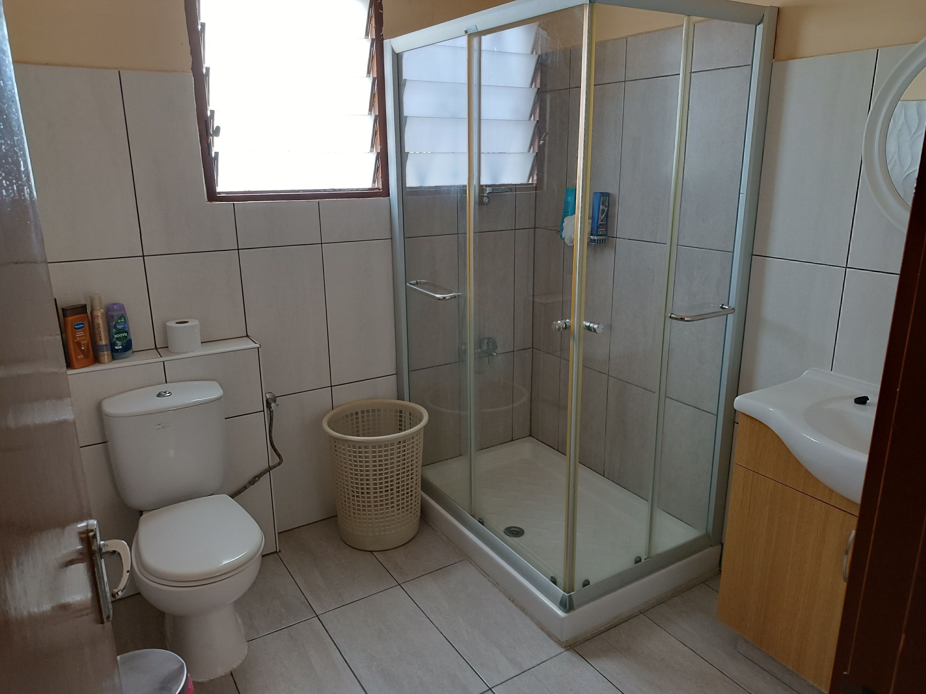 Een badkamer met toilet, een douchecabine, een wastafel en een raam.