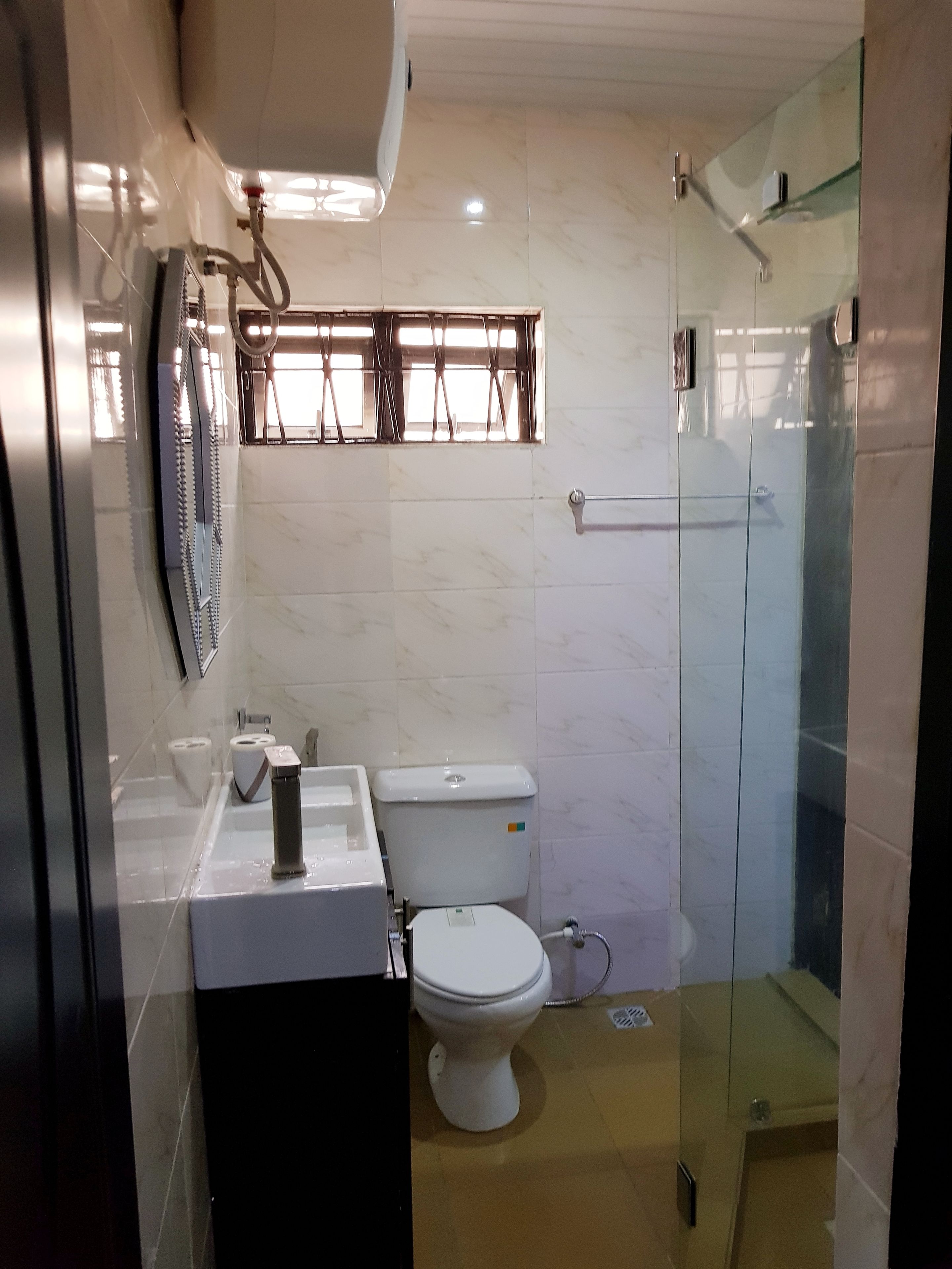Un bagno moderno con cabina doccia in vetro, un water e un mobile lavabo con specchio.