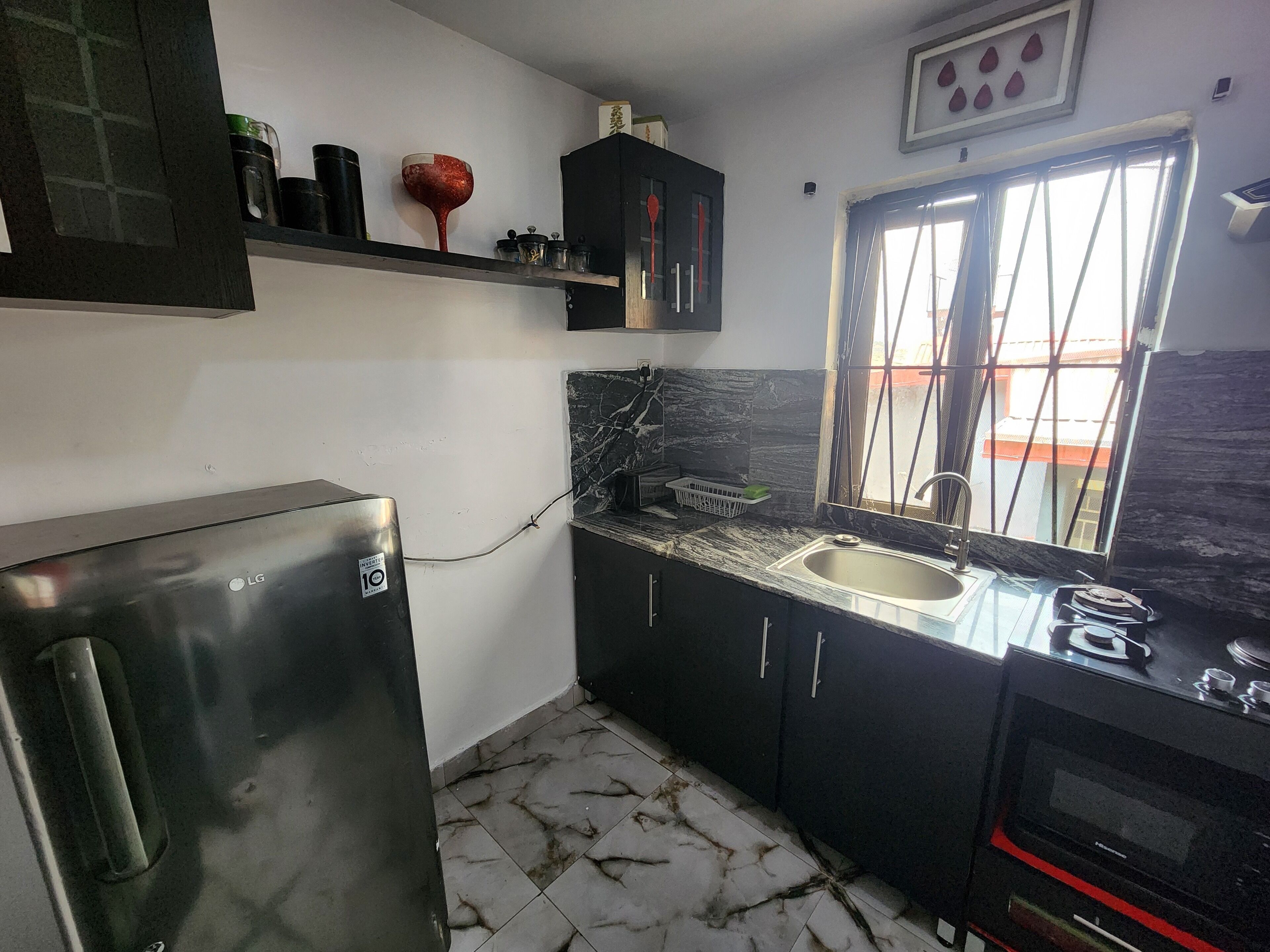 Cocina compacta con refrigerador, pileta y horno. Una ventana ofrece vistas a edificios.