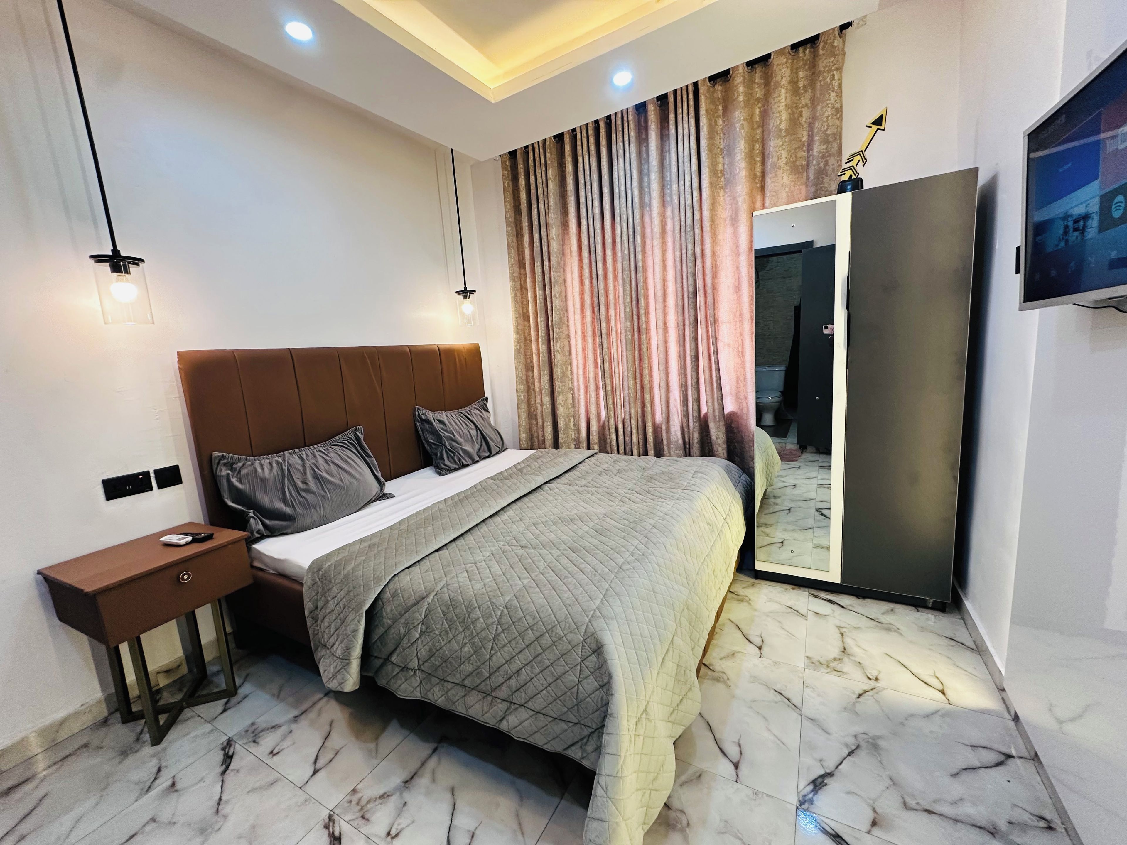 A modern bedroom with a bed, bedside table, and a wardrobe.