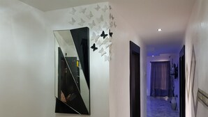Un couloir doté d’un grand miroir, de décorations murales représentant des papillons et d’un sol en marbre.