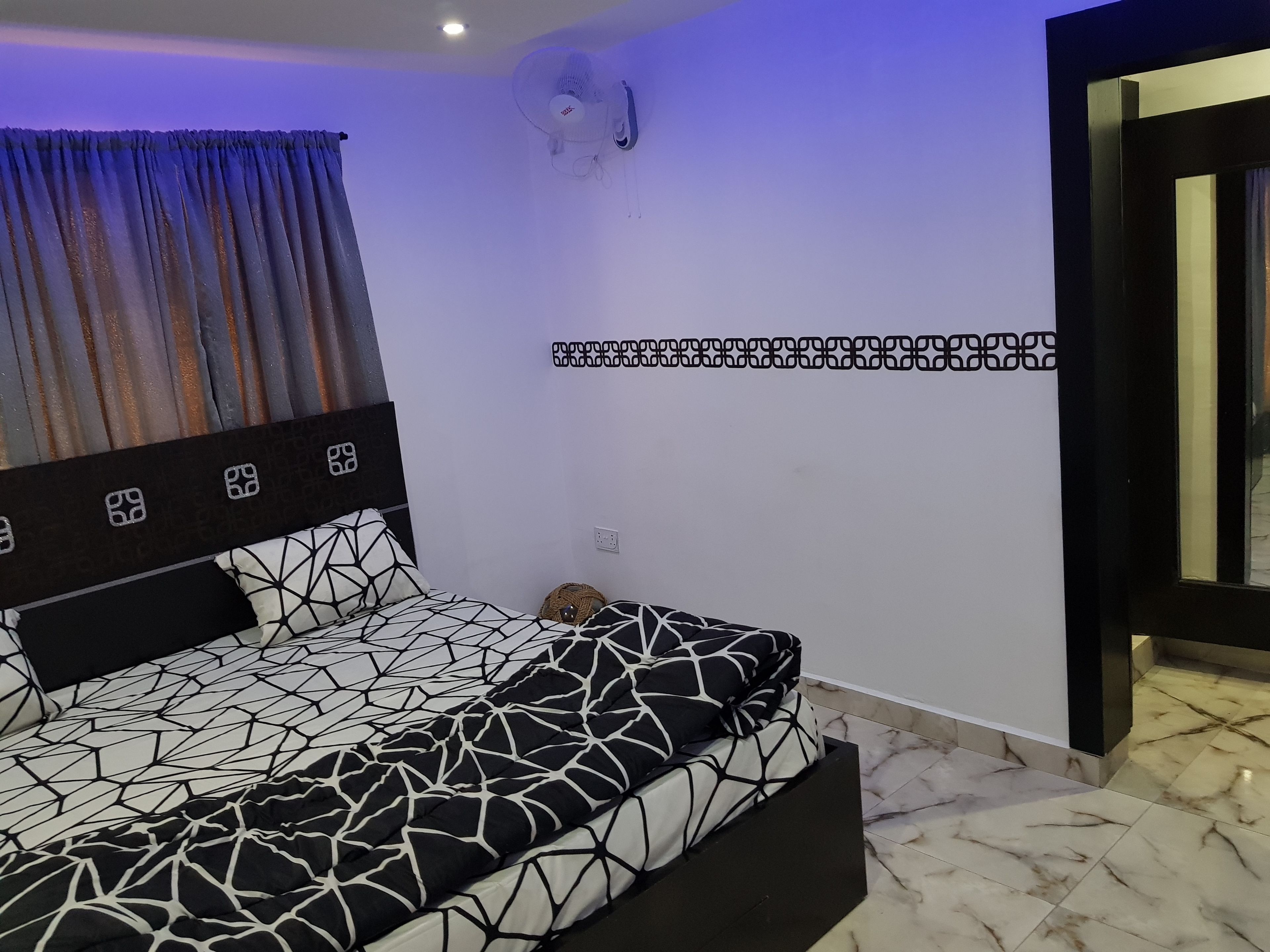 Ein Schlafzimmer mit einem Bett, einem Wandventilator und einer Wanddekoration mit Muster.