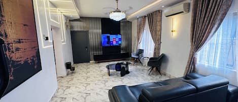 A modern living room with a black leather sofa, a TV, and a ceiling fan.