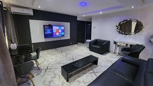 Un salon moderne doté d’un téléviseur à écran plat, d’un canapé en cuir noir et d’un sol en marbre.