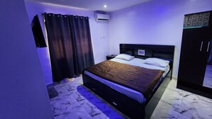 Une chambre à coucher comprenant un lit, une table de chevet, une armoire et un appareil de climatisation.