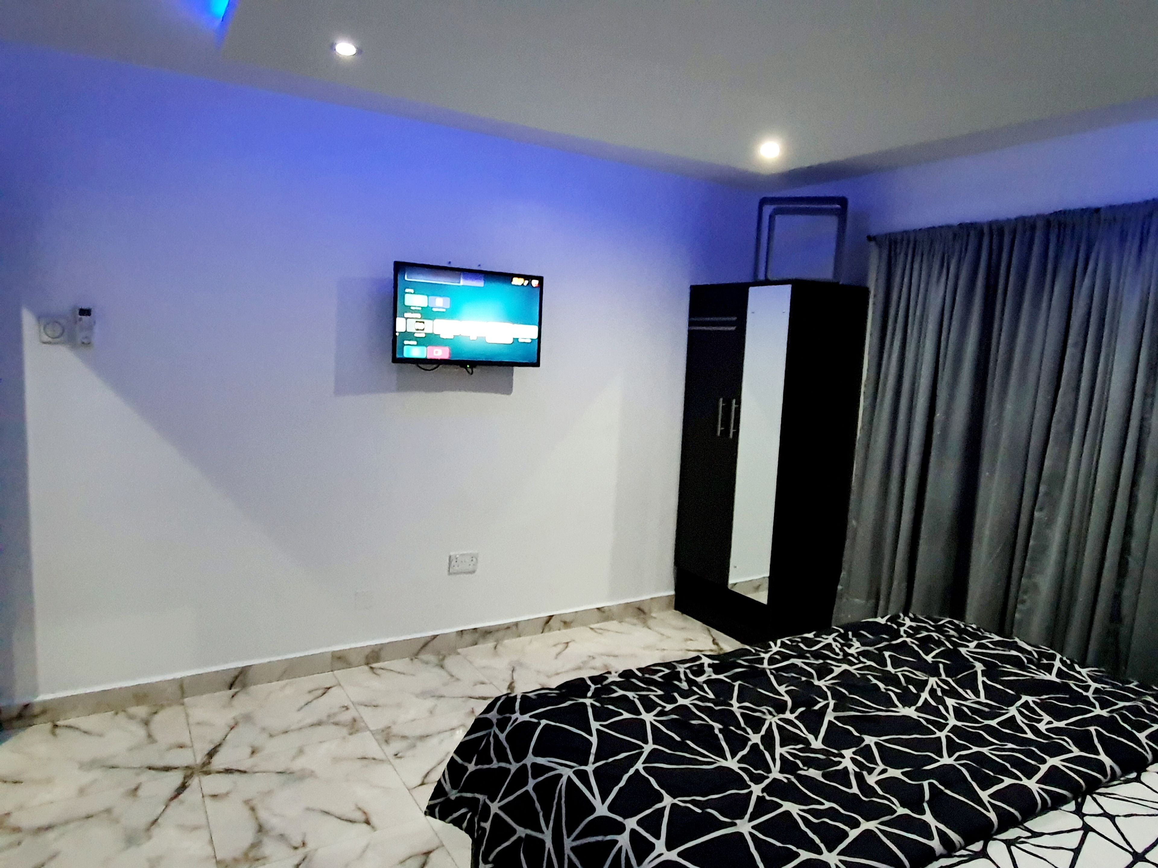 Ein modernes Schlafzimmer mit einem Bett, einem an der Wand befestigten Fernseher und einem großen Spiegel.