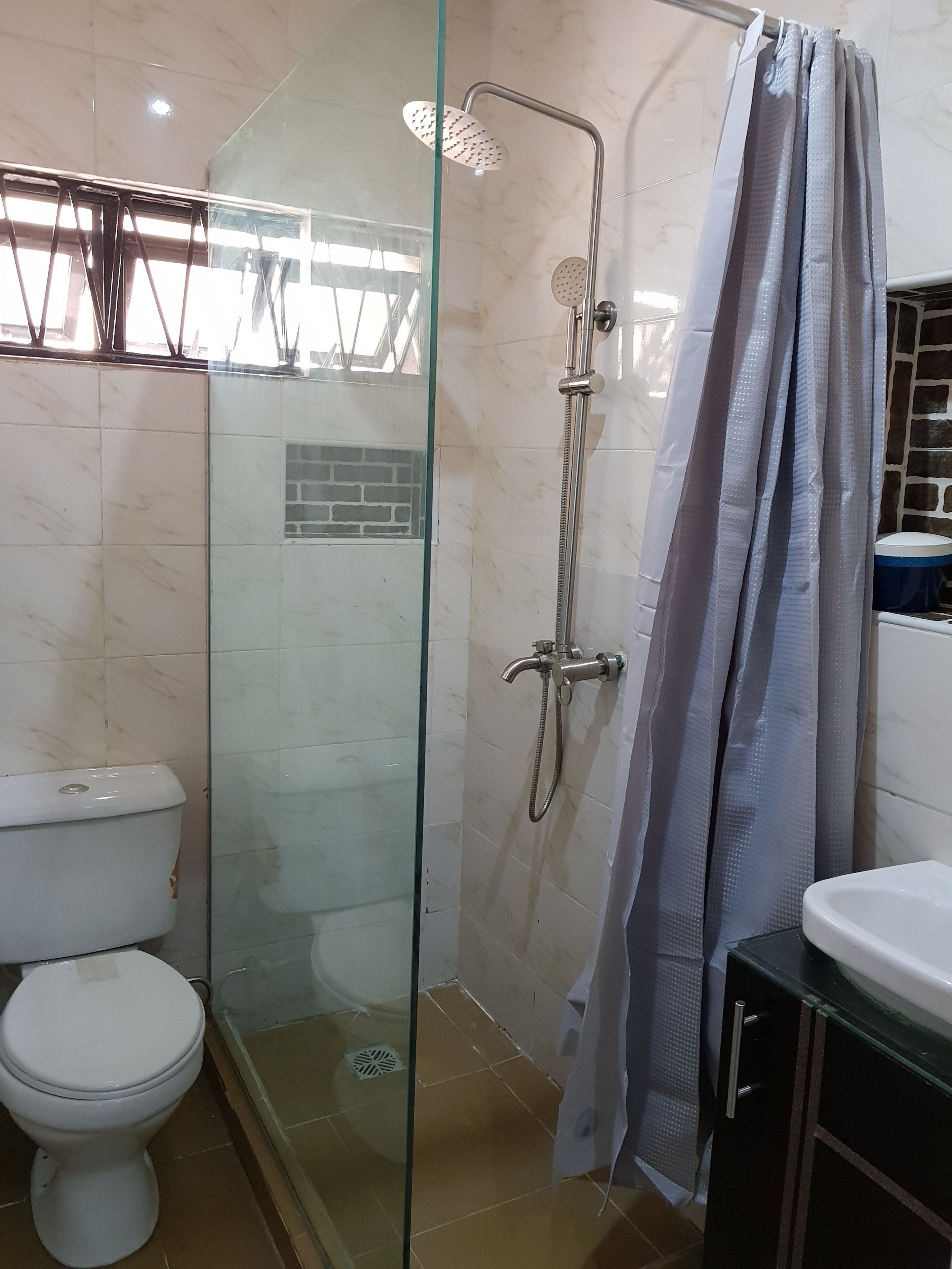 Une salle de bain avec une douche à parois de verre, des toilettes et un lavabo.