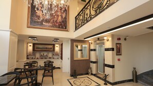 A spacious lobby with a high ceiling, a chandelier, a large painting, and a staircase. - Art Nouveau Pera (Istanbul)